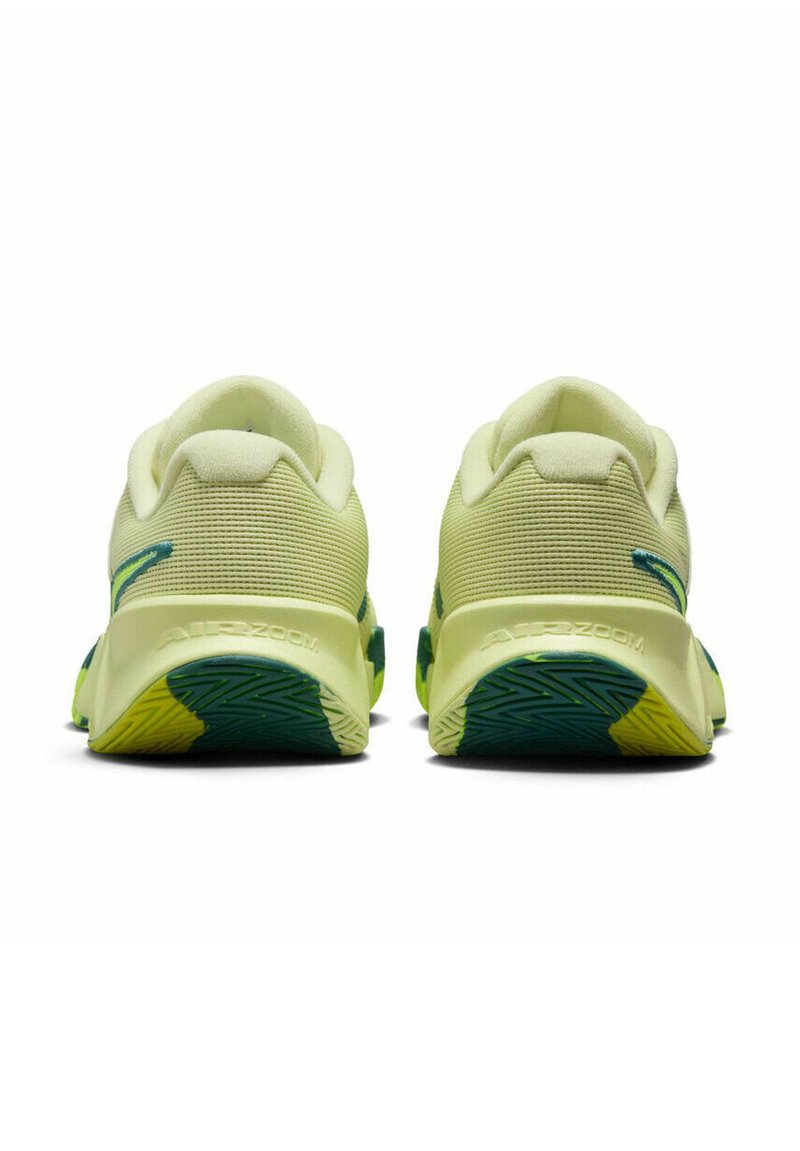 Une paire de chaussures de sport jaune clair avec des semelles vertes et jaunes, montrées de l'arrière avec des cols rembourrés et le logo "AIR ZOOM".