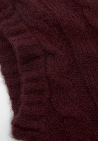 Burgundy knitted fabric with a textured cable pattern, featuring a soft and fluffy appearance. The edges are ribbed, enhancing thickness.
