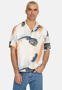 Camisa de manga corta con un patrón abstracto en acuarela en tonos naranjas, azules y blancos; tejido ligero con un corte relajado.