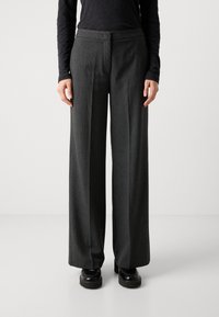 Pantalones de pierna ancha en tela gris oscuro con un sutil patrón de cuadros. Presentan un diseño plano en la parte frontal, corte recto y bolsillos laterales.
