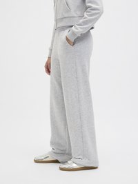 Gray, lightweight sweatpants with a relaxed fit, side pockets, and a soft texture. Paired with silver sneakers featuring a tan sole.