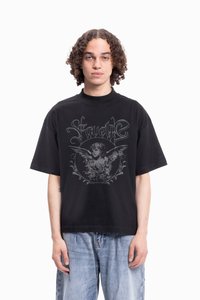 Svart bomull T-skjorte med korte ermer, prydet med et gr�ått grafisk trykk av en engleaktig figur og blomsterdesign på forsiden.