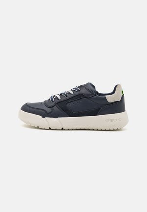 Zapatilla de cuero azul marino con suela de goma blanca, acentos texturizados, perforaciones y detalle en el talón gris contrastante. Cordones en color a juego.