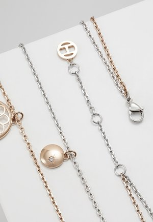 Naszyjniki łańcuchowe w odcieniach złota i srebra z okrągłymi zawieszkami i zapięciem typu lobster, prezentowane na białej powierzchni.