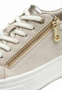 Sneaker beige chiaro con pelle testurizzata, lacci bianchi, una cerniera dorata sul lato e una suola platform bianca.