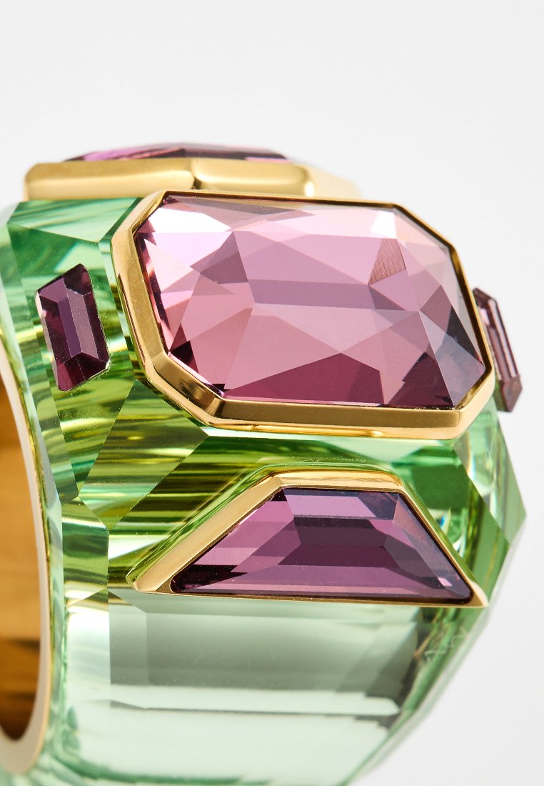 Bracelet vert et or orné de grandes pierres précieuses facettées roses et violettes de différentes formes, avec une finition glossy et un design géométrique.