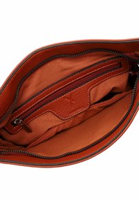 Sarkanā ādas rokassomas iekšpuse ar galveno nodalījumu un rāvējslēdzēja kabatu. Gluda tekstūra, vienkrāsains un redzamas šūšanas detaļas.