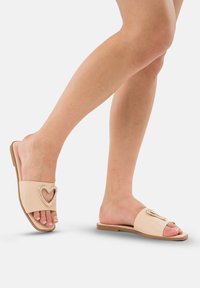 Slide sandalen met een nude synthetisch bovenwerk, voorzien van een hartvormige strassdetail. Vlakke zool met een open teenontwerp.