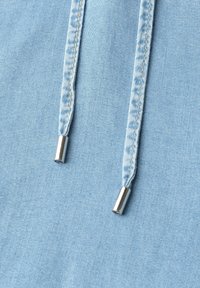 Tissu bleu clair avec deux cordons cousus se terminant par des embouts métalliques argentés.
