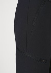 Mustad püksid siledast kangast tekstuurist, mis sisaldavad külgsel zip-taskut ja õmblusdetaili, loodud täiuslikult istuvaks siluetiks.