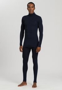 Maglia termica blu navy con collo alto e maniche lunghe, abbinata a leggings aderenti coordinati. Tessuto liscio ed elastico, con cuciture minime.