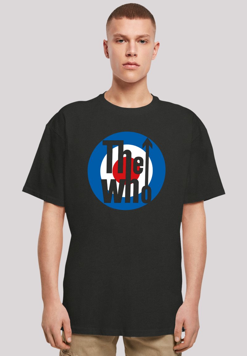 Schwarzes Baumwoll-T-Shirt mit einem runden Logo, das blaue, weiße und rote Elemente sowie den Text "The Who" in fetten schwarzen Buchstaben zeigt.