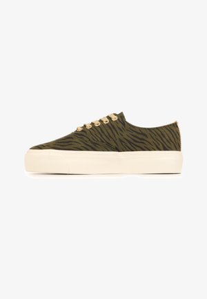 Lage sneaker met olijfgroene en zwarte zebrastripes, beige veters en dikke off-white rubberen zool, zijaanzicht.