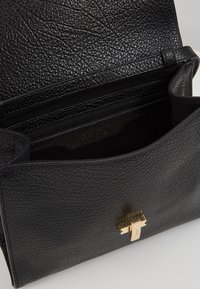 Borsa in pelle nera con superficie testurizzata, accessori in tono oro e scomparto interno con cerniera. Presenta un design sottile e strutturato.