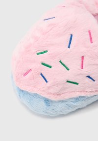 Chinelo de peluche rosa com sola azul, apresenta granulados coloridos em verde, azul, rosa e roxo, textura macia, forma arredondada.
