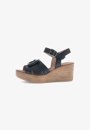 Black leather wedge sandals with a braided texture, featuring a circular buckle accent and an adjustable ankle strap.