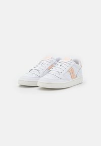Sneakers in pelle bianca con accenti color pesca chiaro, punta perforata, design con lacci e suola in gomma testurizzata. Stile minimalista e linee pulite.