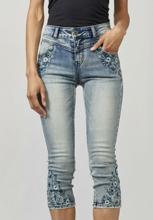 Pantalons capri en denim bleu clair avec broderies florales sur les poches et les bords. Design ajusté avec une taille mi-haute et une fermeture à bouton.