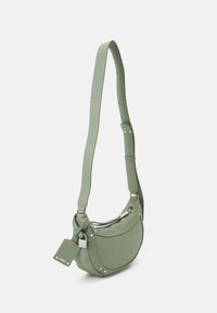 Borsa a tracolla in pelle verde con design curvo, tracolla regolabile, dettagli in metallo argentato e un piccolo cartellino. Superficie testurizzata e chiusura con zip.