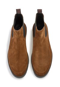 Bottines Chelsea en daim marron avec des panneaux élastiques sur les côtés et une languette. Surface texturée, bout rond et semelle en caoutchouc.