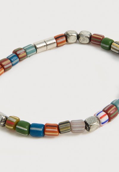 Ελαστικό βραχιόλι με πολύχρωμες ριγέ και μεταλλικές χάντρες σε διάφορα σχήματα, τοποθετημένες σε μια συνεχή θηλιά σε λευκό φόντο.