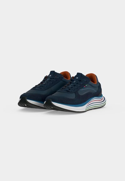 Paire de baskets bleu marine avec doublure intérieure orange et semelles intermédiaires rayées multicolores sur fond blanc.