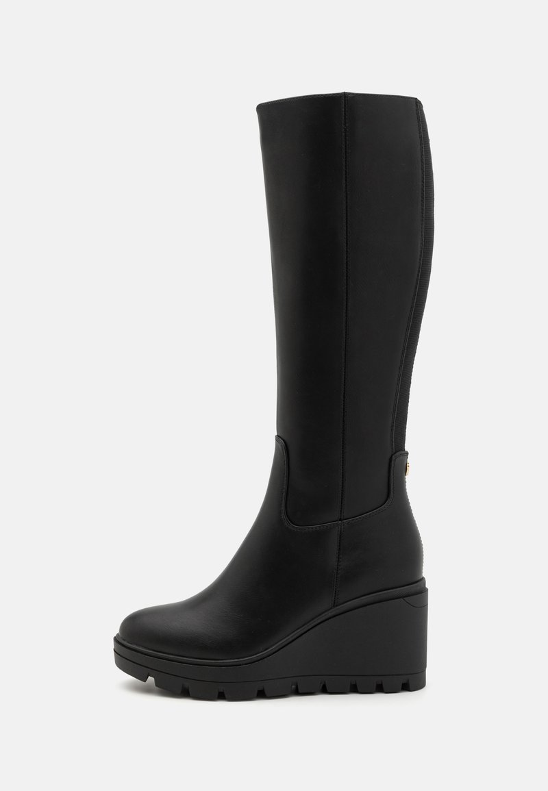 Botas de cuña negras hasta la rodilla, fabricadas en cuero suave con suela de goma texturizada, que presentan un diseño elegante y un sutil acento lateral.