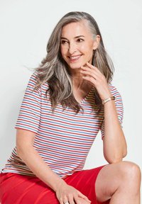 T-shirt à manches courtes et en V avec des rayures rouges et bleues sur fond blanc, associé à une jupe rouge. Texture lisse, design décontracté.