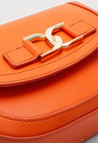 Borsa in pelle arancione con chiusura dorata, caratterizzata da una texture liscia e bordi arrotondati, completata da cuciture a contrasto.