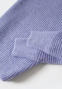 Manches de pull en maille côtelée violet clair pliées et dispersées sur une surface blanche, montrant un tissu texturé et des poignets.