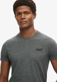 Gray short-sleeve t-shirt made of soft fabric, featuring a round neckline and a small black logo on the left chest.