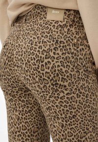 Leopardprint jeans in bruin en zwart met een soepele textuur, met een merkpatch op de tailleband en gestikte zakken.