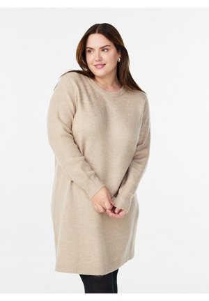 Bežové pletené šaty z mäkkej textúrovanej priadze s dlhými rukávmi a okrúhlym výstrihom. Obsahujú jemné ozdoby na jednom pleci.