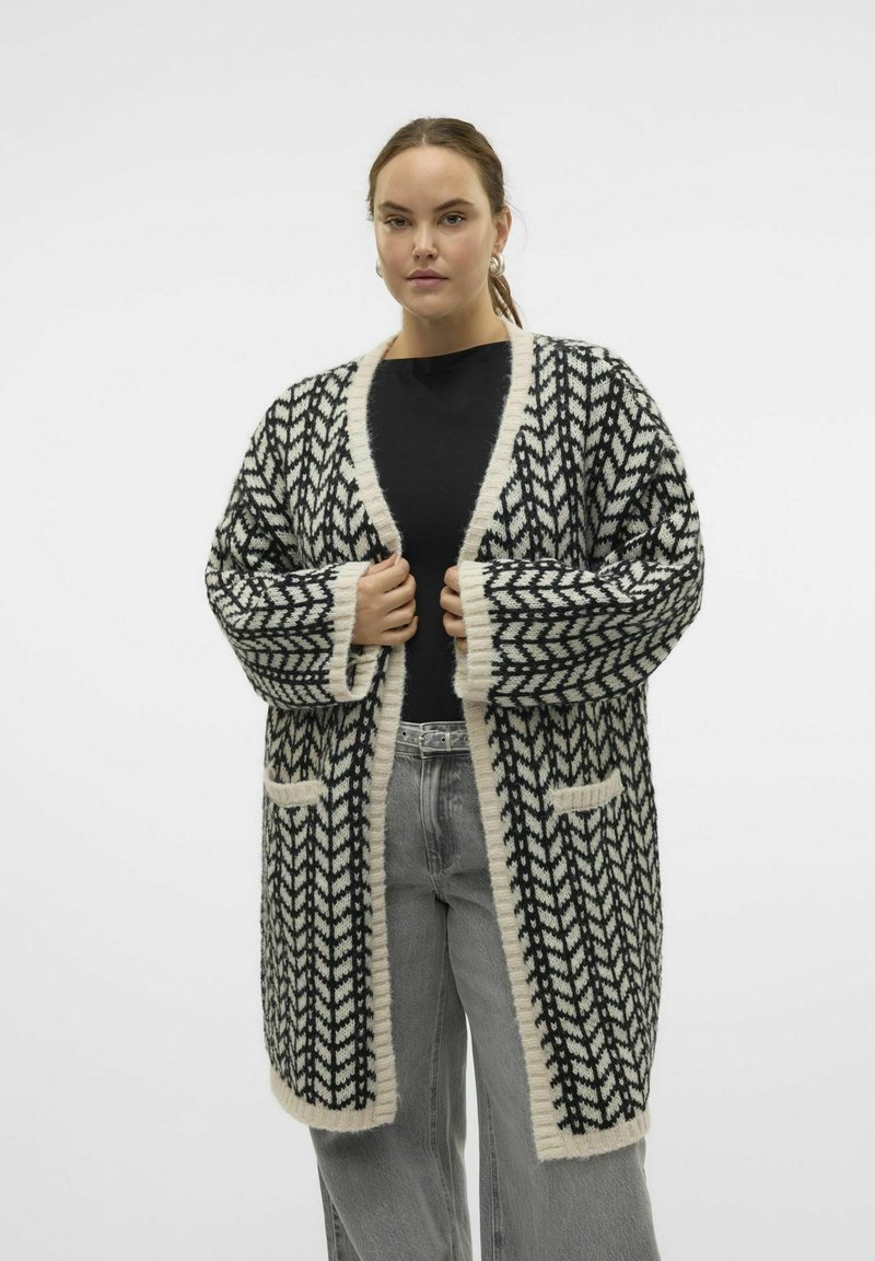 Cardigan à motifs noir et blanc avec devant ouvert, manches larges et deux poches avant. Texture douce avec des bords crème contrastants.