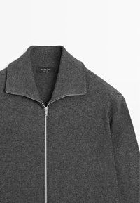 Grijze ritsvest gemaakt van fijne breiwerk, met een hoge kraag en een zilveren rits. Etiket zegt "Massimo Dutti."