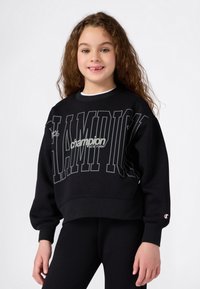 Czarna bluza z dużym białym i szarym napisem "Champion", okrągły dekolt, ściągacze przy rękawach oraz logo na rękawie. Miękka faktura materiału.