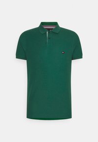 Polo-shirt court à manches courtes de couleur vert foncé avec col, deux boutons noirs et un petit patch logo rectangulaire sur la poitrine gauche.