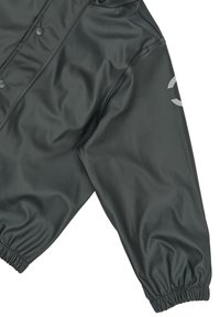 Veste imperméable noire à texture lisse, avec boutons-pression et poignets élastiques. Présente un logo discret sur la manche gauche.