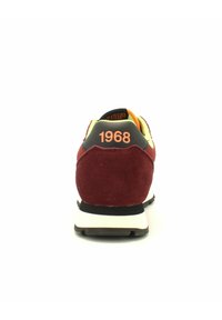 Sneaker rossi e neri con tomaia in suede, suola imbottita e l'anno "1968" stampato in arancione sul tallone.