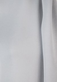 Tessuto azzurro chiaro, liscio e con una consistenza morbida, che mostra pieghe drappeggiate. Il materiale appare leggero e leggermente trasparente.