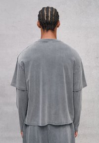 Losse grijze katoenen blend top met korte mouwen en een afgeronde zoom. Zachte textuur met een ontspannen silhouet, met een subtiele vervaagde afwerking.