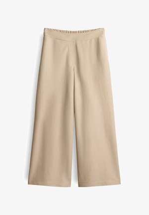 Beige weite Hose mit elastischem Bund, glatter Textur und minimalen Nähdetails, entworfen für Komfort und Leichtigkeit beim Tragen.