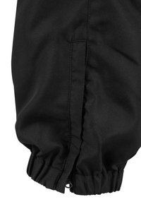 Sort elastisk manchet ved buksebenet med en glat tekstur. Sidesøm detail synlig, hvilket skaber en tætsiddende form ved anklen.