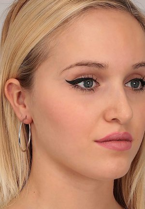 Orecchini a cerchio argentati con un design circolare sottile. Il modello ha capelli biondi lisci, occhi azzurri e trucco sobrio con eyeliner all'ingiù.