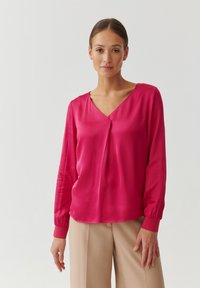 Blusa de manga larga en satén de color rosa brillante, con escote en V y corte holgado. Puños con detalles elásticos; textura suave con ligero brillo.