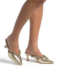 Escarpins slingback métalliques dorés avec un bout pointu et des embellissements en cristal le long de la sangle ; dotés d'un petit talon épais.