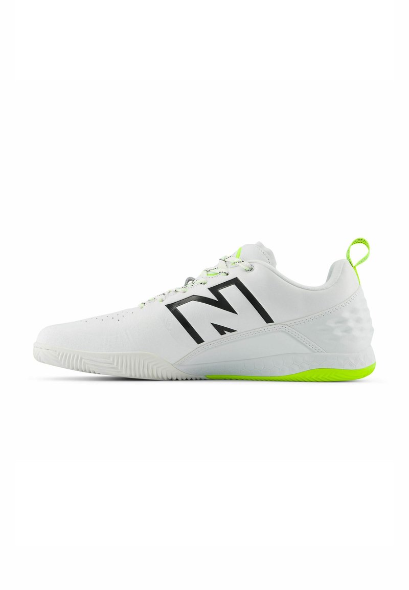 White athletic shoe with black logo, textured upper, and bright green accents on the sole and heel. Features lace-up design and pull tab.