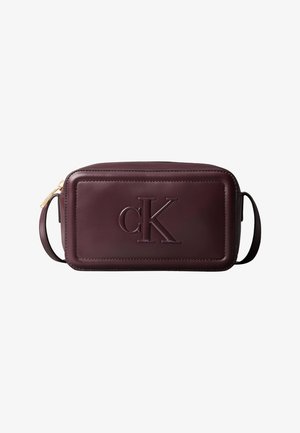 Sac bandoulière rectangulaire en cuir marron foncé avec logo "cK" embossé sur le devant et une fermeture éclair dorée sur un côté.