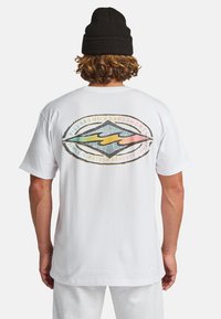 Camiseta de algodón blanca con un gran gráfico colorido en la parte de atrás que presenta una forma de diamante, texto y un diseño de playa.