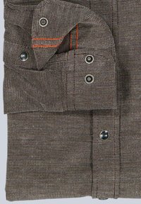 Brauner strukturierten Stoff mit einem gewebten Muster, ausgestattet mit Metall-Druckknöpfen und orangefarbenen Nähakzenten, der ein gefaltetes Design mit Taschen zeigt.